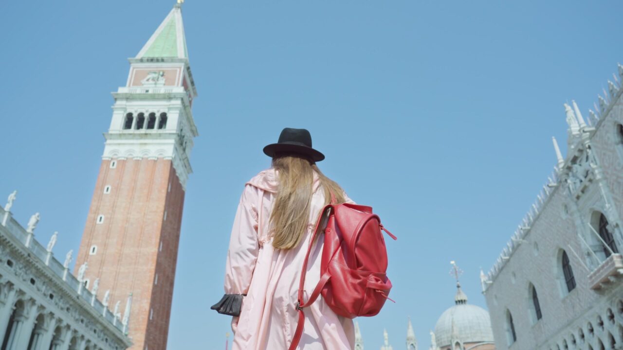 La donna con il cappello nero cammina su Piazza San Marco in una giornata di sole