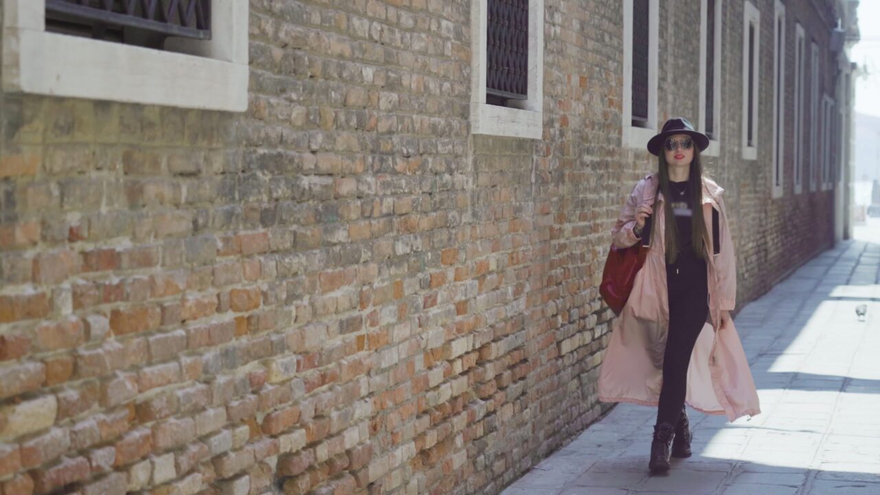La donna cammina sulla strada oltre l’edificio in mattoni marroni a Venezia