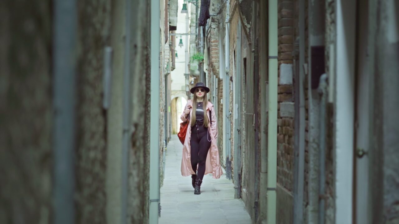Donna sicura in abito elegante cammina su una strada stretta