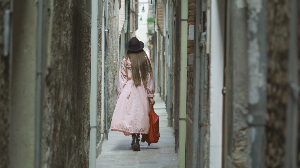La donna con i capelli lunghi cammina sulla via stretta a Venezia