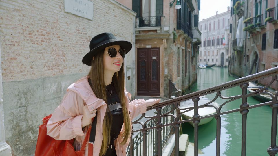 Il turista della donna cammina sul ponte di metallo sopra il canale a Venezia