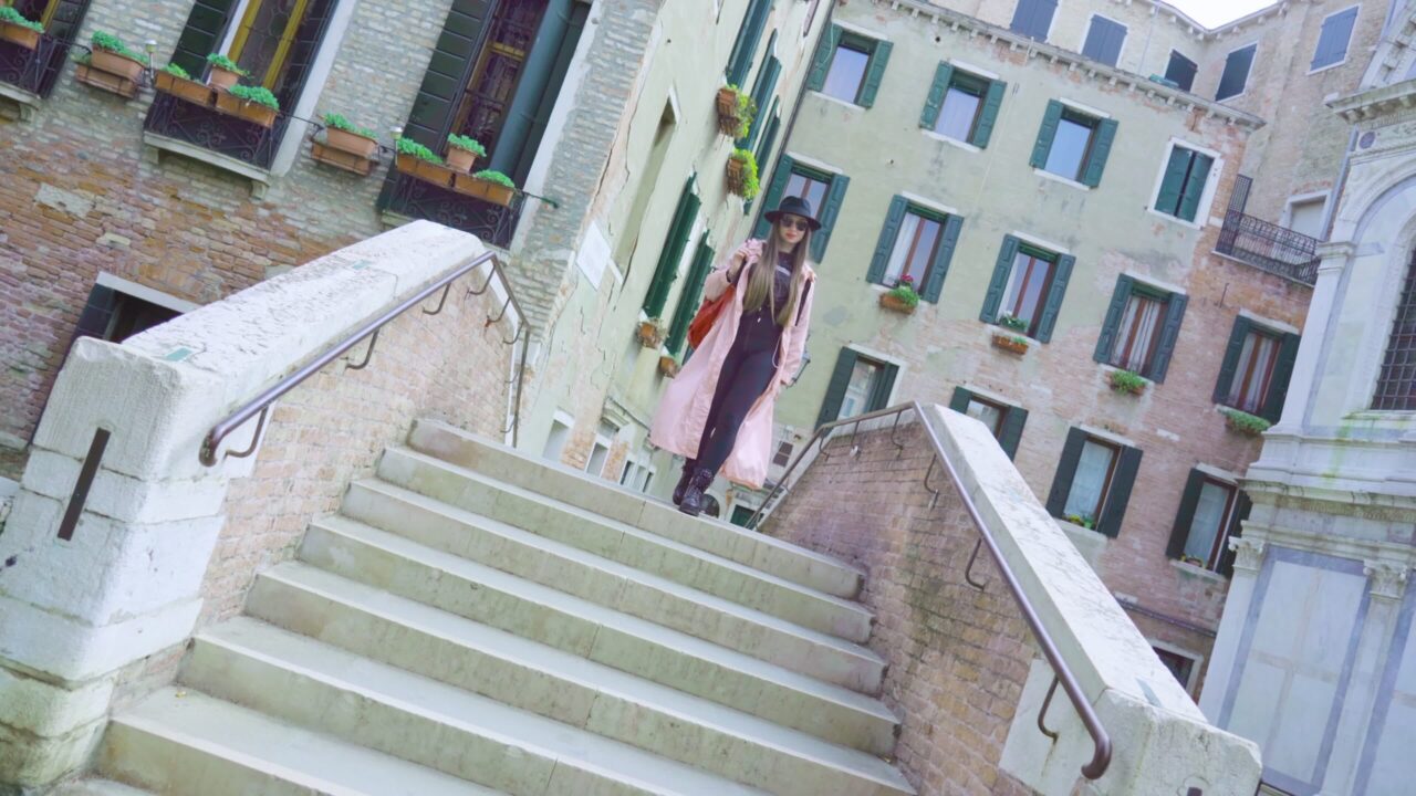 La donna cammina sulle scale del ponte davanti edifici d’epoca