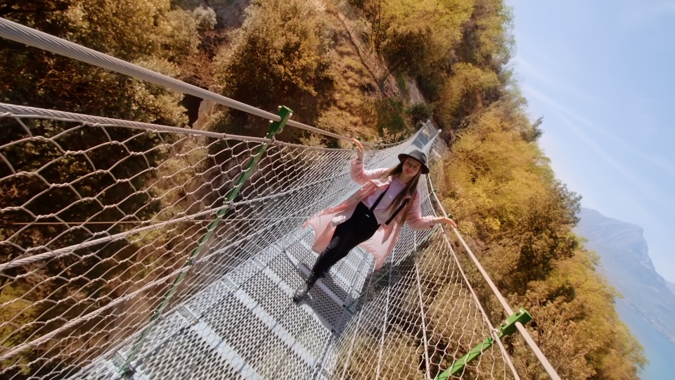 Woman enjoys walking on bridge over yellowed trees in park