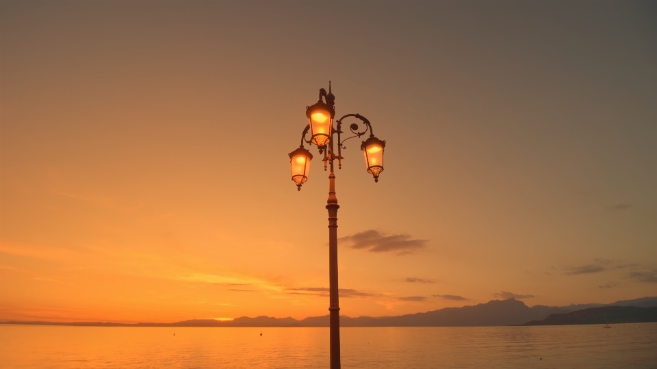 Bright street lantern built on city embankment against lake