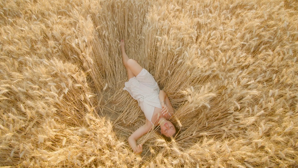 Young woman enjoys relaxing in ripe wheat field on sunny day