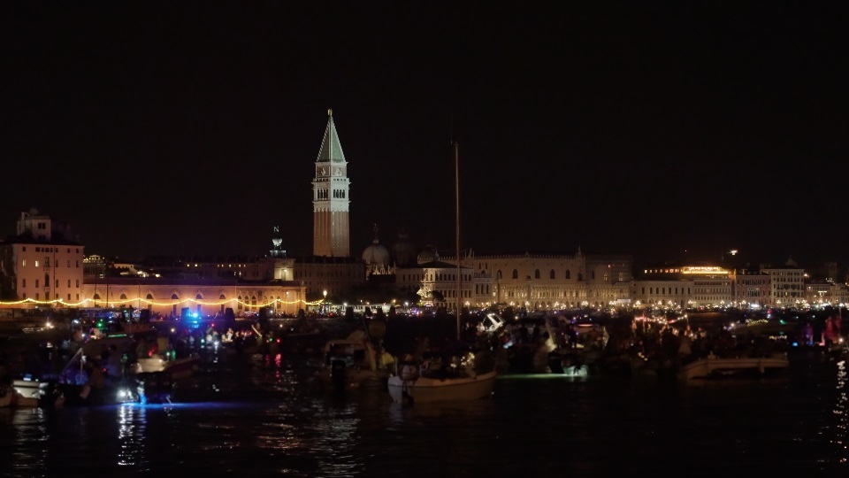 People sail on traditional lit Venetian boats at night