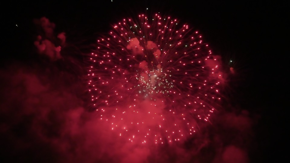 Colorful fireworks explode in night sky spreading smoke