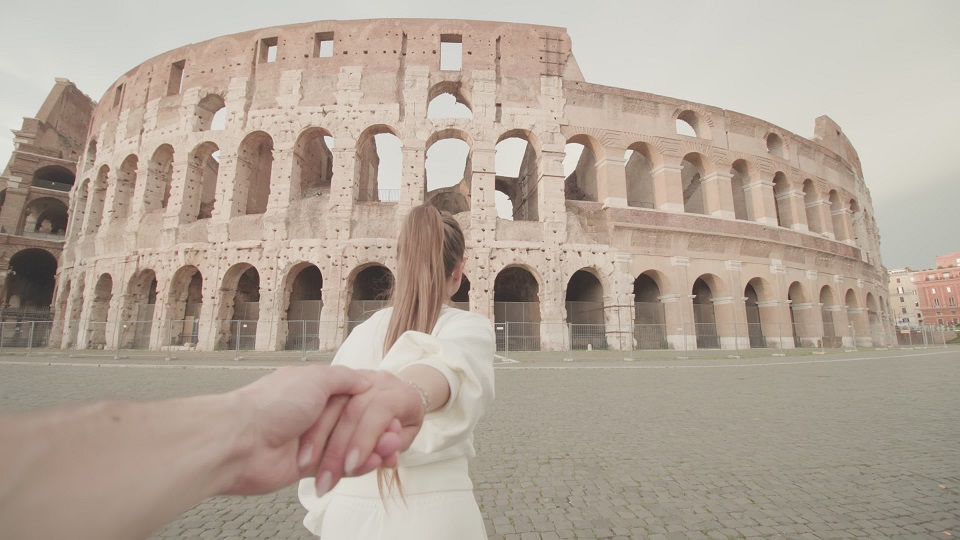 Woman holds hand of man walking to large Colosseum in Rome