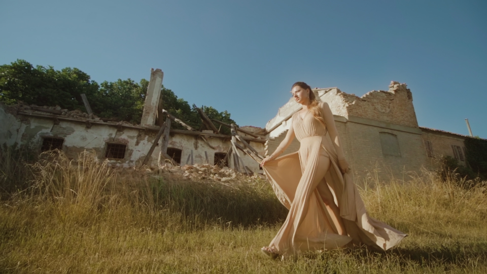 Beautiful elegant woman walks in front of ruined building