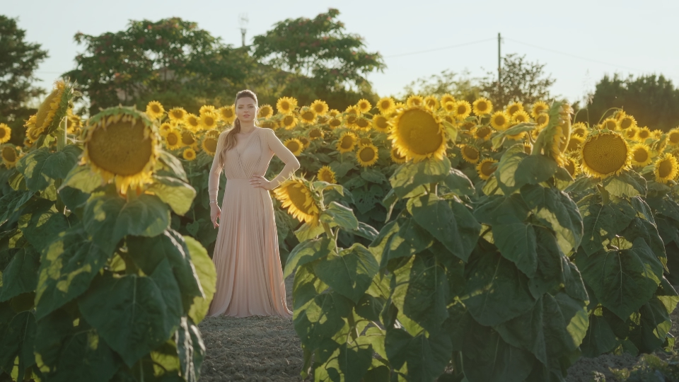Elegant model standing among bright sunflowers