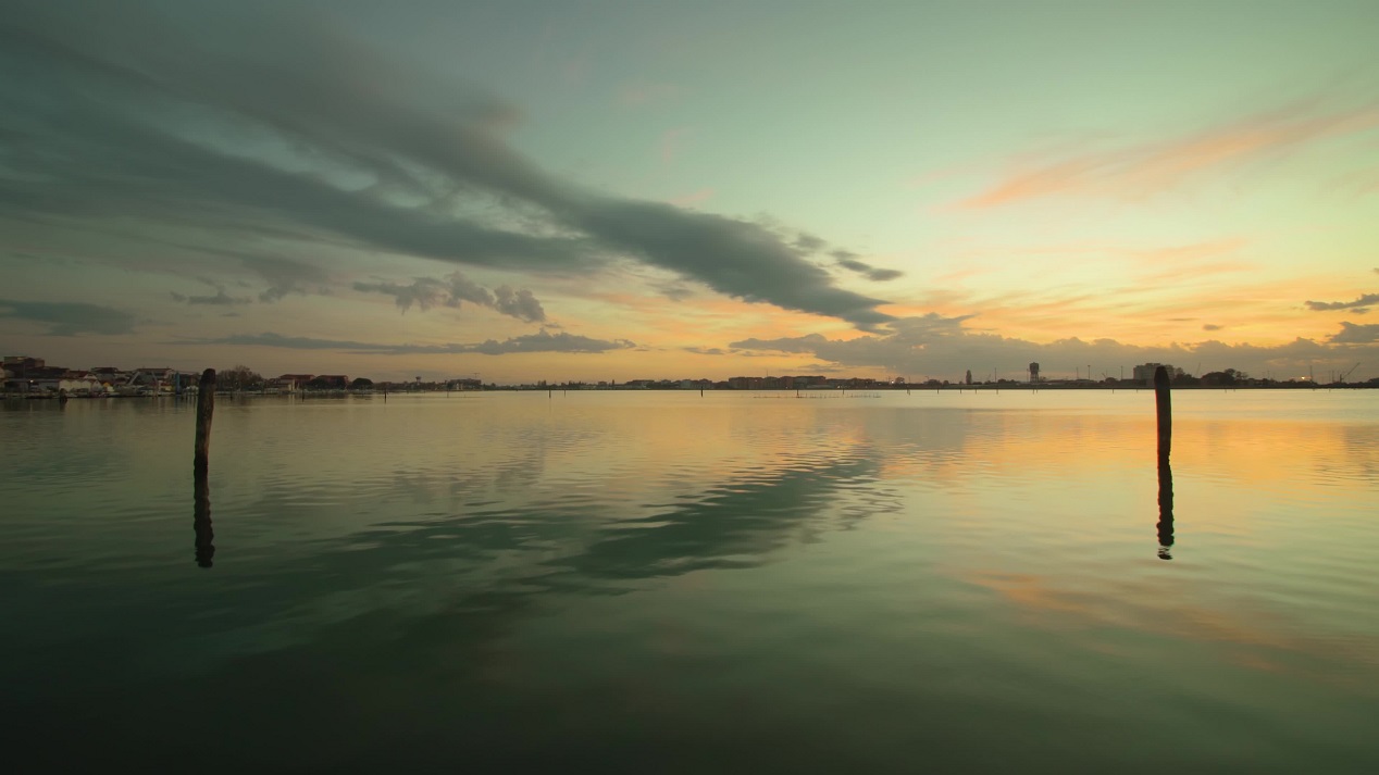 Acqua della laguna di Venezia con riflesso del cielo nuvoloso al tramonto