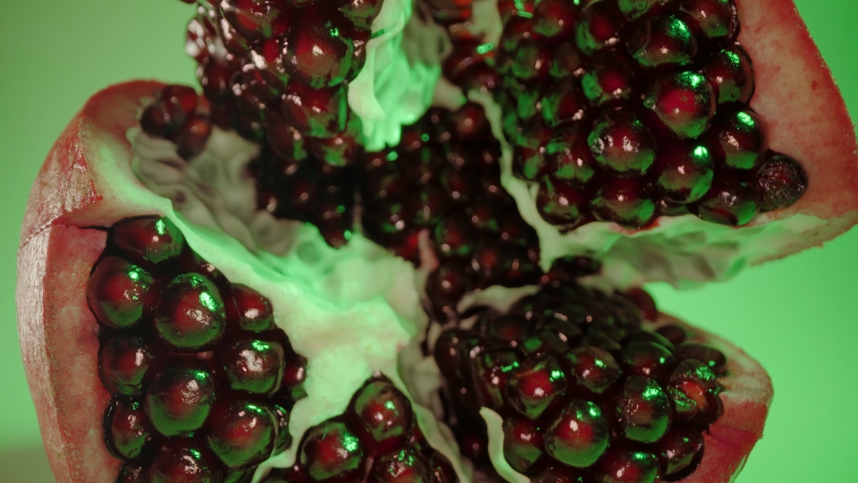 Delicious pomegranate with juicy red grains on light green