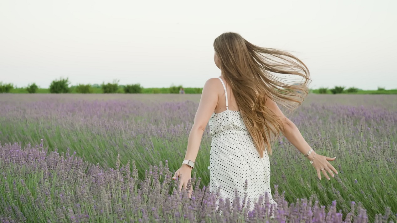 Beautiful young woman runs on the green lavender field