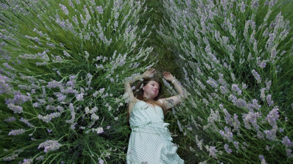 Woman with white dress lying in the green lavender