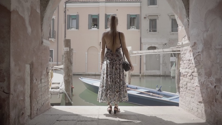 La donna guarda la barca sull’acqua del canale veneziano