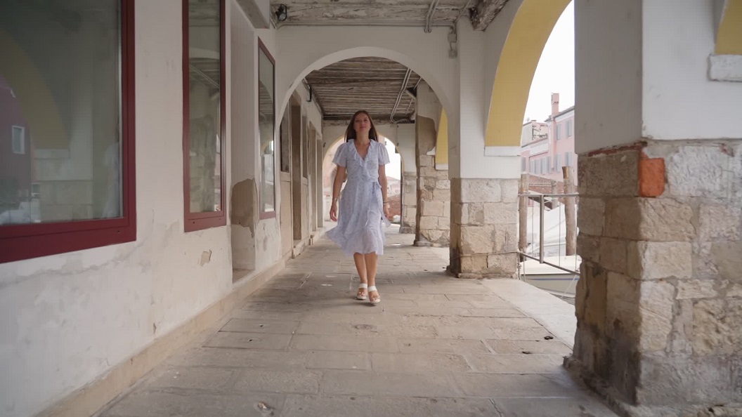 Young woman walks under Venetian arcades