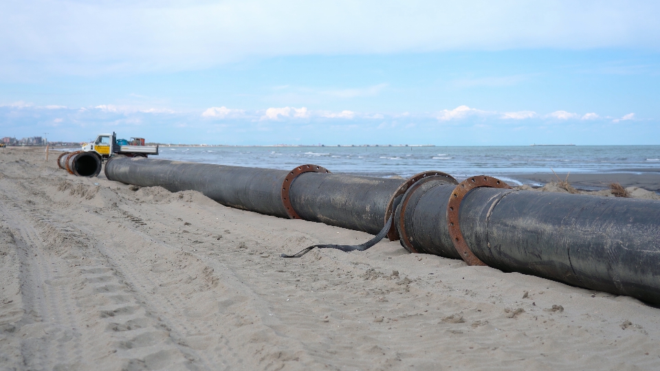 Linea di tubi in spiaggia per lo spostamento della sabbia