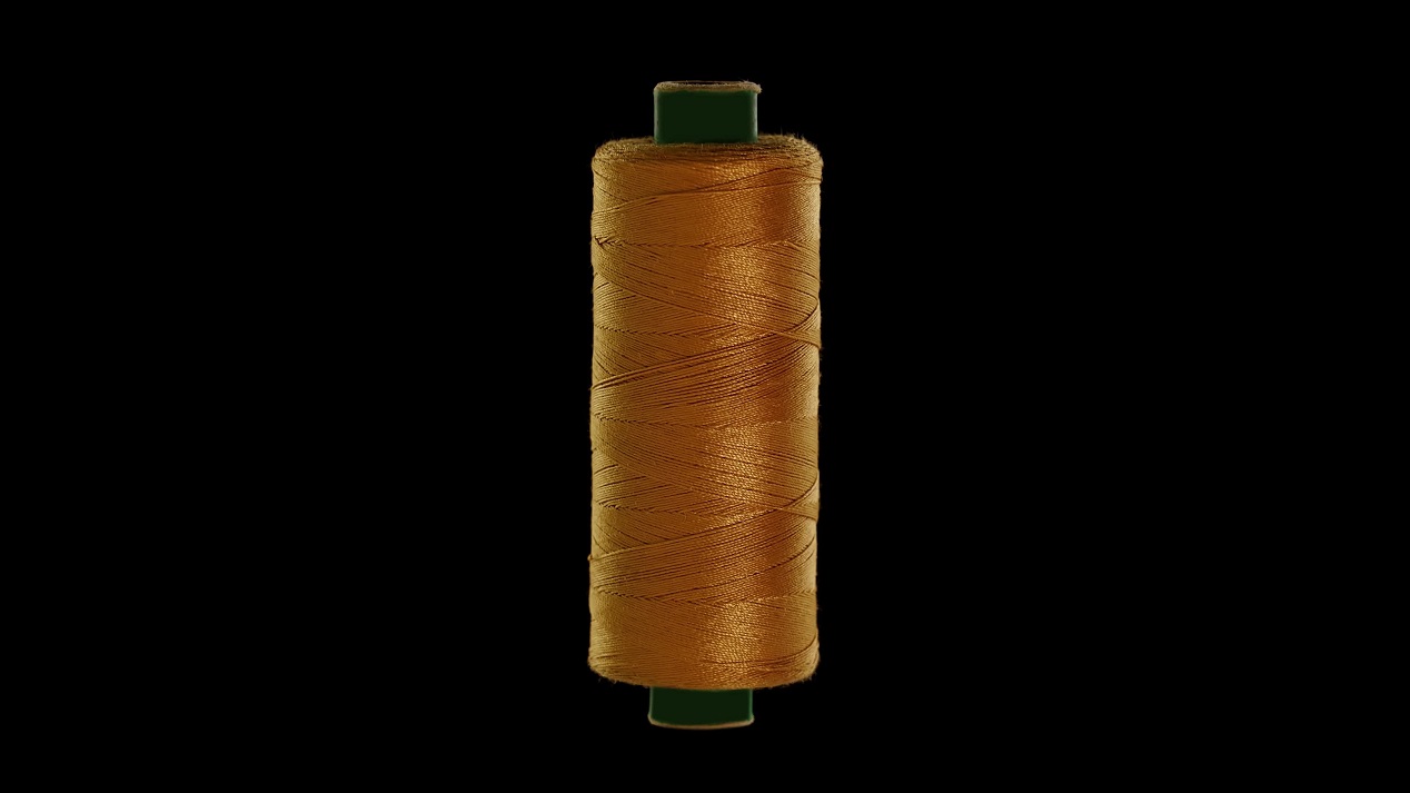 Gold colored sewing thread on a black background