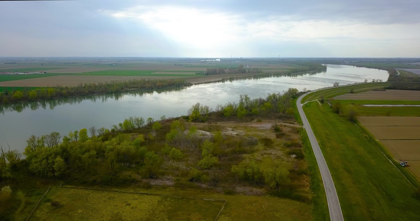 Aerial view of the Po river between green fields and a road