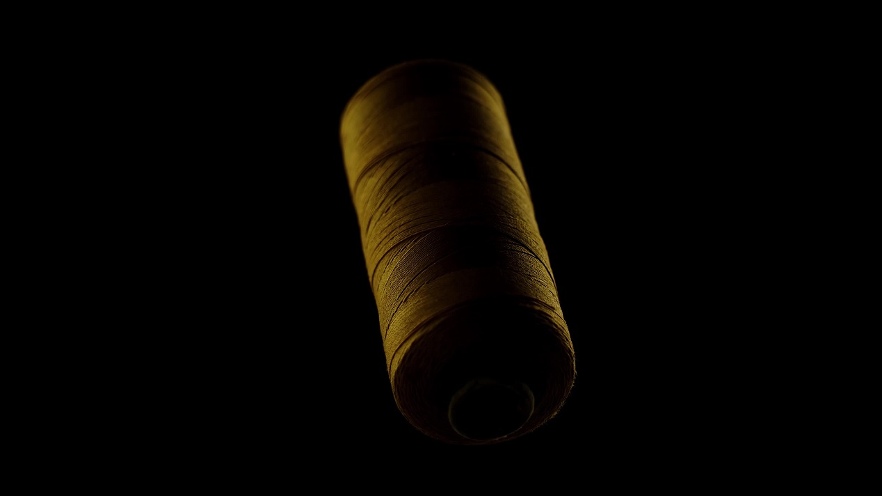 Gold colored sewing thread on a black background