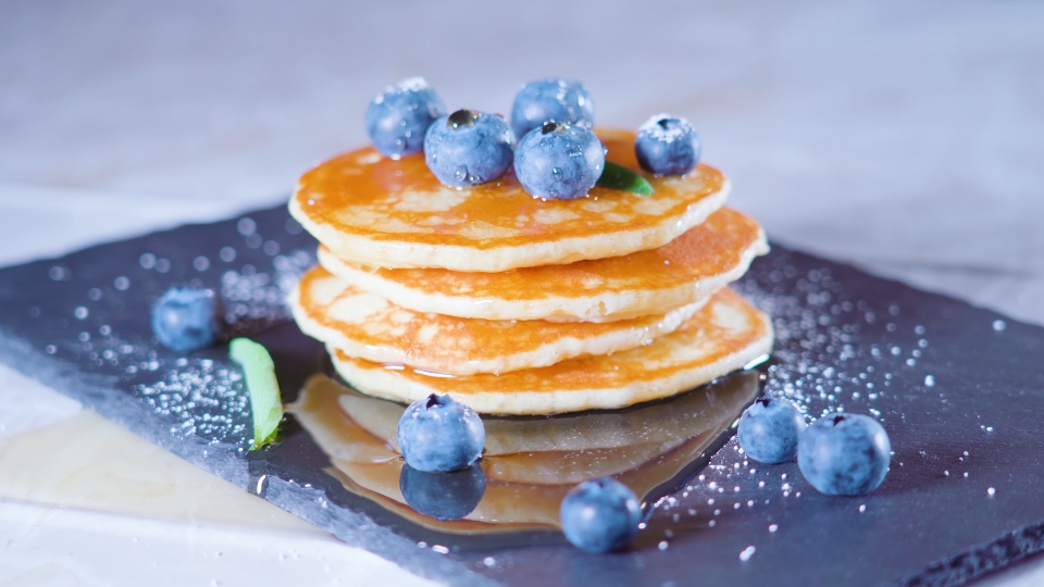 Blueberries on top of pancakes with syrup around