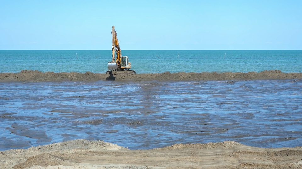 Excavator quickly moves to the sides to the construction site on the beach